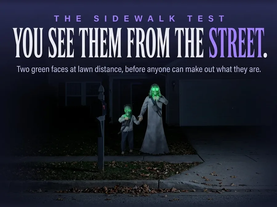 The two figures seen small from the public sidewalk at night, two green points where the faces are.