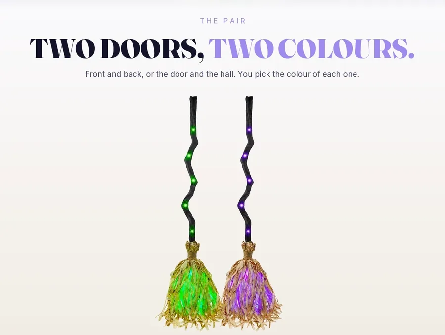 Two brooms side by side on pale studio paper, one lit green and one lit violet